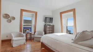 um quarto com uma cama e 2 cadeiras e uma televisão em Sail Inn Lunenburg em Lunenburg