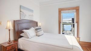 a white bedroom with a bed and a window at Sail Inn Lunenburg in Lunenburg