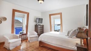 een slaapkamer met een bed en 2 stoelen en een televisie bij Sail Inn Lunenburg in Lunenburg