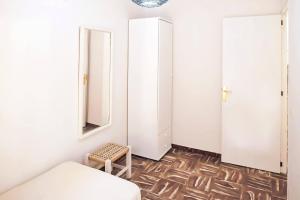 1 dormitorio con paredes blancas, 1 cama y 1 taburete en Apartamento Ses Botges - Formentera Break, en Es Caló