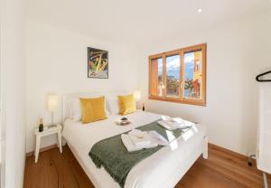 a white bed in a room with a window at Chalet Stella Alpina in Wengen