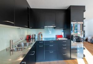 a kitchen with black cabinets and a sink at Chalet Stella Alpina in Wengen