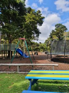 a playground with a bench and a swing at Kauri Coast TOP 10 Holiday Park in Kaihu