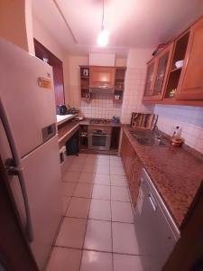a kitchen with a refrigerator and a tile floor at Marina Agadir appartement in Agadir