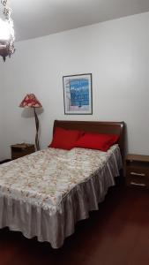 a bedroom with a bed with a red pillow at Casa Aconchegante - Circuito Teresópolis Friburgo in Teresópolis