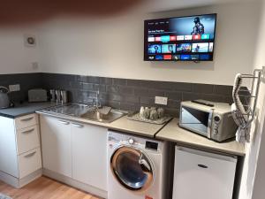 a kitchen with a washing machine and a tv on the wall at The Annexe in Rothwell