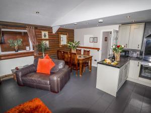 a living room with a leather couch and a kitchen at The Roe in St Asaph