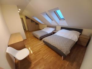 an attic bedroom with two beds and a chair at Apartament Lusowo in Lusowo