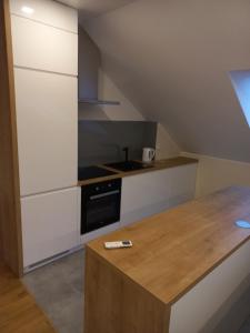 a kitchen with white cabinets and a wooden counter top at Apartament Lusowo in Lusowo
