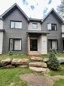 a gray house with rocks in front of it at Jasmin Townhouse Lac Moore, Mont-Tremblant in Mont-Tremblant