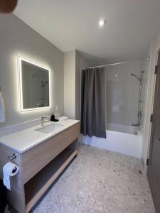 a bathroom with a sink and a mirror and a tub at Jasmin Townhouse Lac Moore, Mont-Tremblant in Mont-Tremblant
