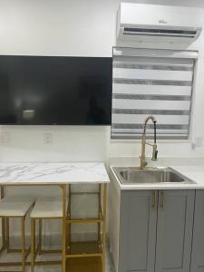 a kitchen with a sink and a counter with stools at Stunning Deluxe Studio in Hialeah