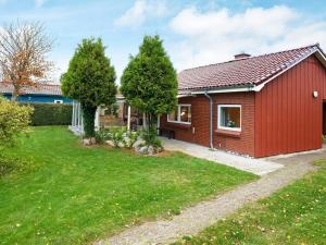 a red house with a green yard at 6 person holiday home in Dannemare in Nakskov