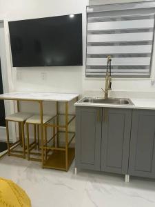 eine Küche mit einem Waschbecken, einem Tisch und einem TV in der Unterkunft Stunning Deluxe Studio in Hialeah