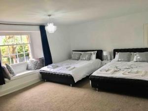 1 dormitorio con 2 camas y ventana en Spacious Countryside/Suburban Retreat-Warwickshire en Walsgrave on Sowe