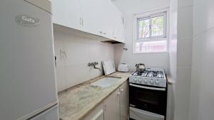 a white kitchen with a stove and a sink at EL DESCANSO a 400 metros del mar departamento 1 ambiente dividido in Mar del Plata