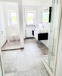 a white bathroom with a toilet and a sink at Schöne Wohnung auf der Schwäbischen Alb in Münsingen