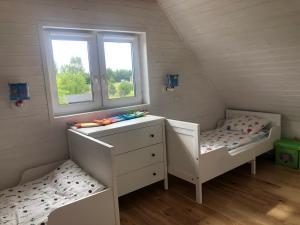 a bedroom with two beds and a dresser and two windows at Joniec Świata - 2 domy na wyłączność in Joniec