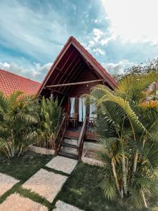 una casa con techo rojo y algunas palmeras en Gayatri Bungalows, en Nusa Penida