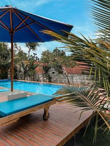 una sombrilla azul sentada en una terraza de madera junto a una piscina en Gayatri Bungalows, en Nusa Penida