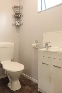 a white bathroom with a toilet and a sink at Kauri Coast TOP 10 Holiday Park in Kaihu