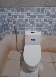 a white toilet in a bathroom with a tile wall at DUMAHOSTEL in Daro