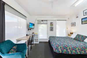 a bedroom with a bed and a desk with a computer at Bundaberg Coral Villa Motor Inn in Bundaberg