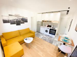 a living room with a yellow couch and a kitchen at Matisse No9 - One Bedroom City Center Apartment With Parking in Tirana