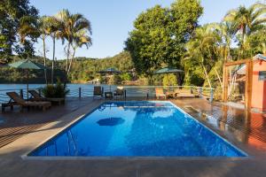 una piscina con terrazza accanto a un bacino d'acqua di Pousada Piratas do Barro Branco a Pedregulho