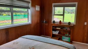 1 dormitorio con 1 cama y 2 ventanas en Waiora cottage, en Otaki