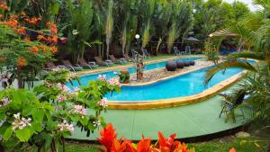 una piscina en un complejo con sillas y flores en Hotel Heliconias Nature Inn & Hot Springs, en Fortuna