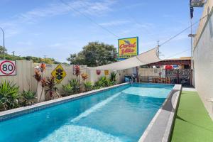 una piscina con sombra sobre ella en Bundaberg Coral Villa Motor Inn, en Bundaberg