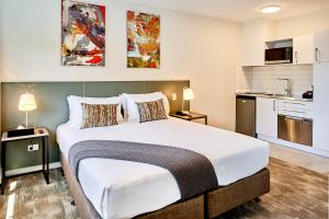 a bedroom with a large bed and a kitchen at Sojourn Apartment Hotel - Ghuznee in Wellington