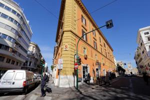 Un uomo che attraversa una strada davanti a un edificio giallo di La Flavia Design City Suites Rome a Roma