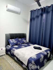 a bedroom with a bed with a blue curtain at Ana Homestay D'Airport in Melaka