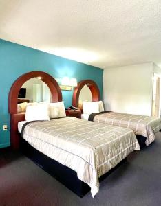 two beds in a hotel room with blue walls at Luxury Inn & Suites in Selma