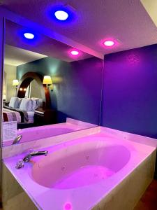 uma grande banheira rosa com luzes roxas num quarto em Luxury Inn & Suites em Selma