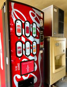 uma máquina de refrigerante de cocacola sentada numa sala em Luxury Inn & Suites em Selma