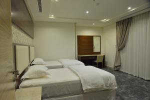 a hotel room with two beds and a desk at حياة إن للأجنحة الفندقية -جده in Jeddah