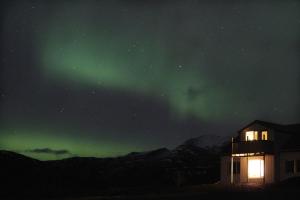 a house with a green aurora in the sky at Sauðanes Guesthouse in Höfn