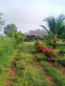 a dirt road in front of a house with flowers at Bo Cabin in Garden โบคาบิน อิน การ์เดน in Ban Nong Ki