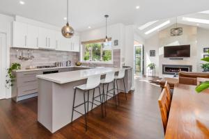a kitchen with white cabinets and a large island with bar stools at Bangalow Mornington in Mornington