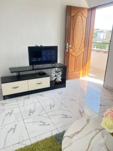 een woonkamer met een tv en een marmeren vloer bij Studio meublé Cosy in Douala