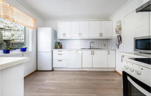 a kitchen with white cabinets and a white refrigerator at Amazing Home In Strandebarm With House Sea View in Strandebarm