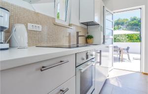 a white kitchen with a sink and a window at Beautiful Home In Milna With House Sea View in Milna