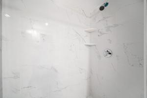 uma casa de banho branca com um chuveiro com paredes em mármore branco em Easy Commute South Boston 4BR 1BH Apt em Boston