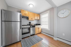 a kitchen with a stainless steel refrigerator and a clock at Easy Commute South Boston 4BR 1BH Apt in Boston