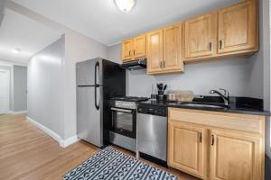 a kitchen with wooden cabinets and a stainless steel refrigerator at Easy Commute South Boston 4BR 1BH Apt in Boston