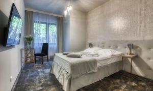 a bedroom with a bed and a chair and a television at Hotel & Spa Biały Dom in Gliwice