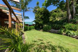 a garden with a lawn in front of a house at Aotea Lodge Escape Packages in Tryphena